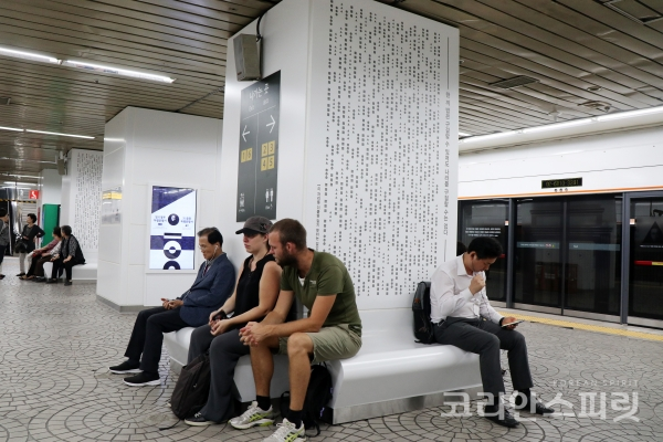 8개의 주제로 독립운동가들 이름을 새긴 ‘100년 걸상’에 시민들이 앉아 지하철을 기다리고 있다. [사진=김경아 기자]