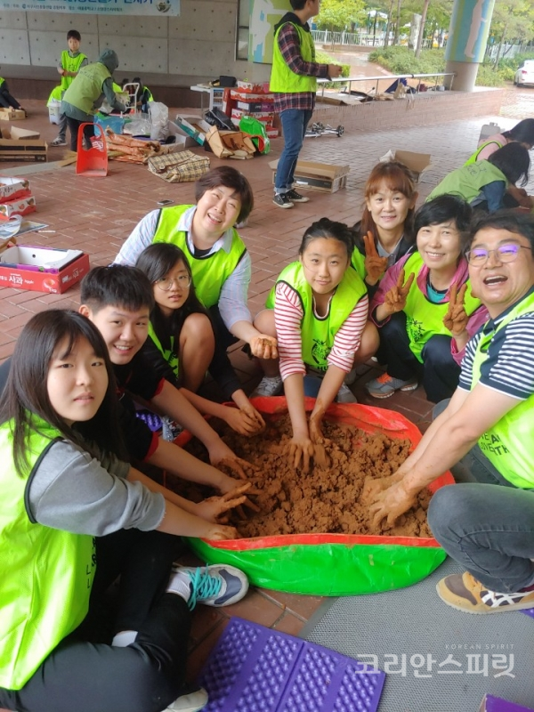 지구시민운동연합 강원지부의 '소양강을 살리는 EM흙공던지기 캠페인'에 참가한 시민들과 학생들이 EM흙공을 만들며 환하게 웃고 있다. [사진=지구시민운동연합 강원지부]