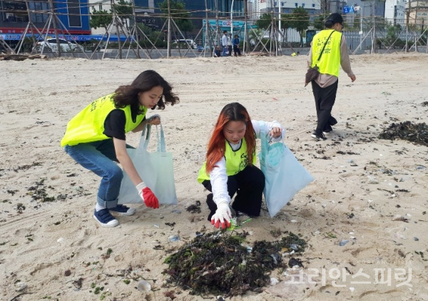 일산 해수욕장 해안정화활동에 참석한 봉사자들이 해변가의 쓰레기를 폐현수막을 재활용하여 만든 가방에 담고 있다. [사진=지구시민운동연합 울산지부]