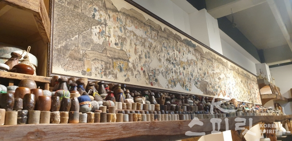 서민들이 쓰던 민속품을 독특하게 전시한 비움박물관 1층 전시장 한 벽면을 가득채운 그림 '장날'. 오일장 풍경 속에 1천 명의 사람들이 각기 제 할일을 하고 있다. [사진=강나리 기자]