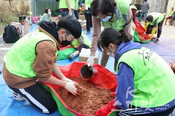 자원봉사자들이 EM용액과 발효액을 진흙에 섞어 반죽을 만들고 있다. [사진=김경아 기자