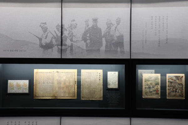1907년 메켄지 기자가 찍은 의병들의 사진을 배경으로 아래 한일병탄 공표문, 그리고 오른쪽에 프랑스    지에 게재된 구한말 처형당하는 군인들. [사진=강나리 기자]