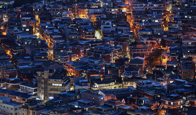 서울 해방촌, 2021, 106×172.5cm. 질서와 변화가 혼재된 이곳의 불 켜진 다세대 주택들은 ‘풍경으로서의 건축’이 아니라 건축물을 넘어서 도시적 삶의 세부를 들여다보려는 작가의 또 다른 면모를 보여준다.  사진 동대문디자인플라자