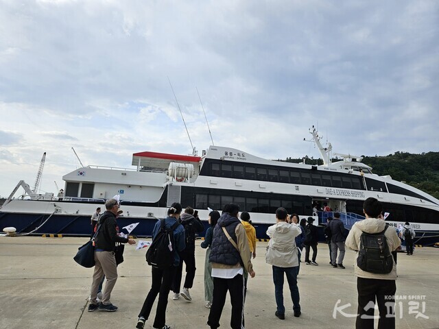 울릉도 사동항에서 독도를 향해 떠나는 배 앞에 삼삼오오 태극기를 든 방문객들이 사진을 찍고 있다. 사진 강나리 기자.
