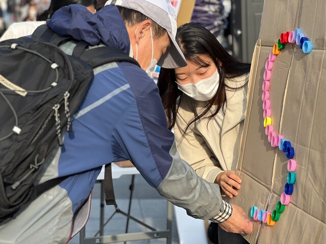 폐페트병 뚜껑으로 '플라스틱 STOP’을 완성하는 병뚜껑 아트 챌린지에 참여하는 시민. 사진 지구시민연합.