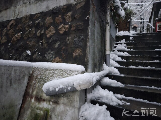 새벽녘 묵묵히 눈을 쓸어 길을 내는 주민. 사진 강나리 기자.