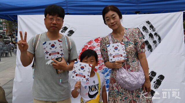 시민들의 손도장으로 완성한 태극기 앞에 선 윤하영(오른쪽), 이재영(왼쪽)부부와 아들. 사진 강나리 기자.